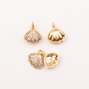 May include: Three gold-tone seashell charms. Two of the charms are closed and one is open. The closed charms are decorated with clear rhinestones. The open charm has a smooth, shiny finish.