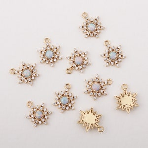 May include: Nine gold snowflake charms with clear opal stones in the centre. The charms have a loop at the top for attaching to jewellery.