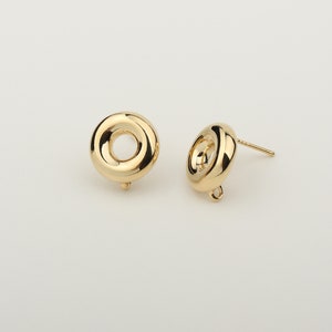 Op de afbeelding: Een paar gouden oorbel-sluitingen met een rond, hol centrum. De sluitingen hebben een pen en een lus om een ​​bedel of hanger aan te bevestigen.
