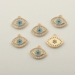 Könnte beinhalten: Sechs goldfarbene böse-Augen-Anhänger mit blauem und türkisfarbenem Emaille und klaren Strasssteinen. Die Anhänger haben die Form eines Auges und eine Öse oben zum Anbringen an Schmuck.