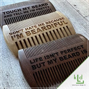 May include: Three wooden beard combs with different sayings engraved on them. The top comb says "Touch my beard and tell me I'm pretty". The middle comb says "Don't hate me because I'm beardful". The bottom comb says "Life isn't perfect but my beard is".