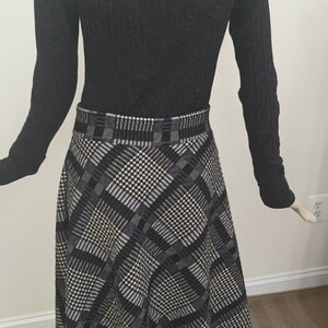 May include: A black and white plaid skirt with a ruffled hem. The skirt is made of a soft, knitted fabric and has a high waist.