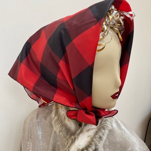 May include: A red and black plaid headscarf tied around a mannequin's head. The scarf is made of a silky fabric and has a slightly shiny finish.