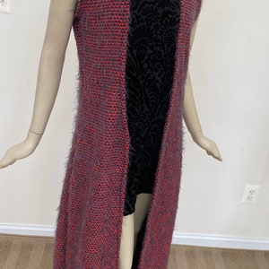 May include: A long, sleeveless, open-front cardigan in a fuzzy, pink and gray knit. The cardigan is shown on a mannequin.