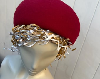 May include: A bright pink felt beret with a gold and white ribbon trim.