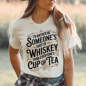 May include: White t-shirt with the text "I'd rather be someone's shot of whiskey than everyone's cup of tea" in a decorative font. The shirt is short-sleeved and has a crew neck.