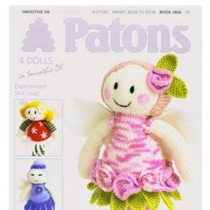 Puede incluir: Un folleto de patrones de tejido de punto con cuatro muñecas para tejer con hilo Smoothie DK. La portada presenta una muñeca de hada rosa y blanca con hojas verdes y flores rosas. El título del folleto es "Patons" y el texto "4 Dolls in Smoothie DK" también es visible.