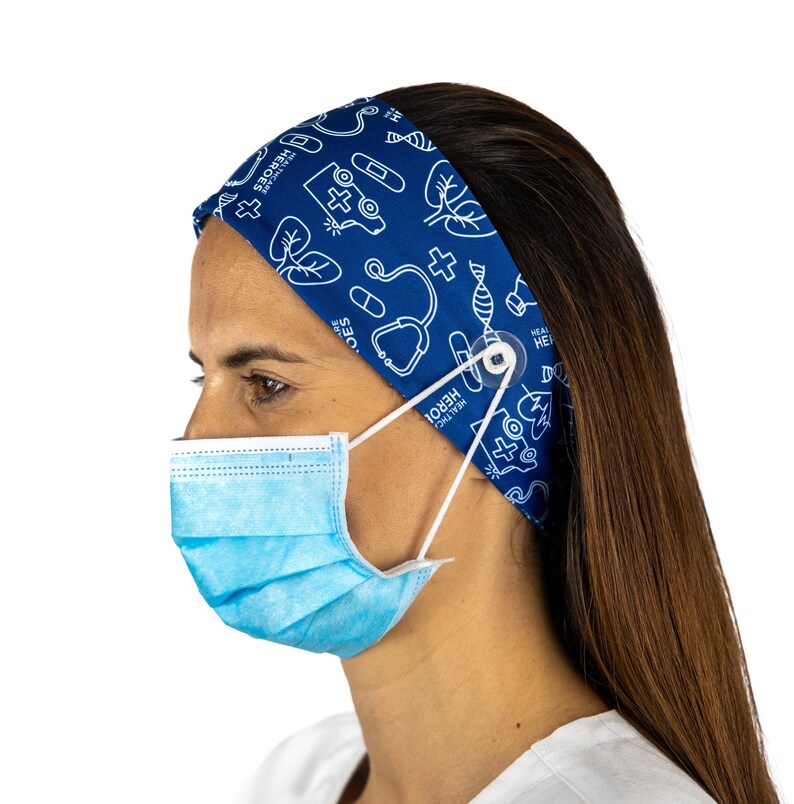 May include: A blue headband with a white print of medical symbols, including a stethoscope, a cross, a heart, and a pill bottle. The headband has a button on the side to hold a face mask in place. The headband is worn by a person with long brown hair.