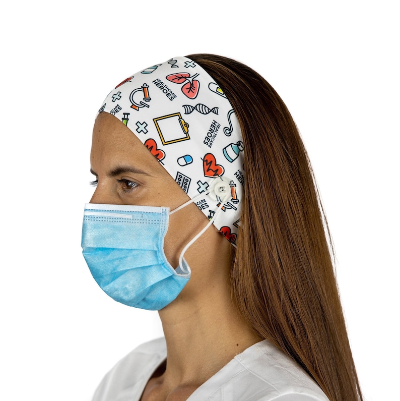 May include: White headband with a colorful pattern of medical symbols and the text "Healthcare Heroes". The headband has a button on the side for attaching a face mask.