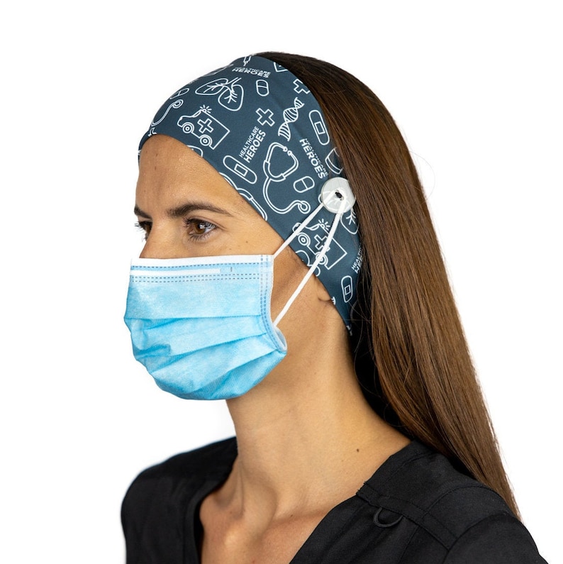 May include: A dark blue headband with a white print of medical symbols and the text "Healthcare Heroes". The headband has a button on the side to hold a face mask.