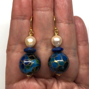 May include: Gold dangle earrings with a blue and gold cloisonn&eacute; bead, a lapis lazuli bead, and a white pearl.
