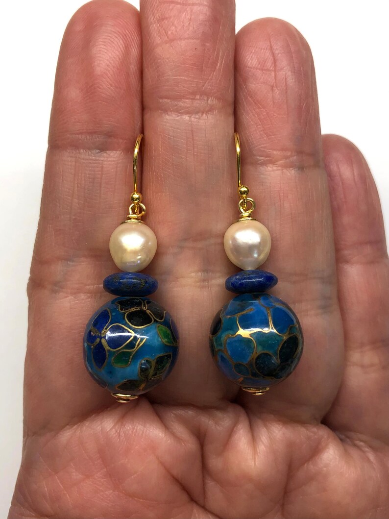 May include: Gold dangle earrings with a blue and gold cloisonn&eacute; bead, a lapis lazuli bead, and a white pearl.