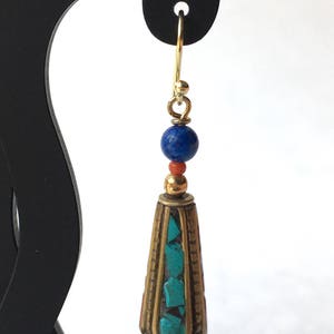 May include: Gold dangle earrings with a turquoise and coral stone cone pendant and a blue lapis lazuli bead.