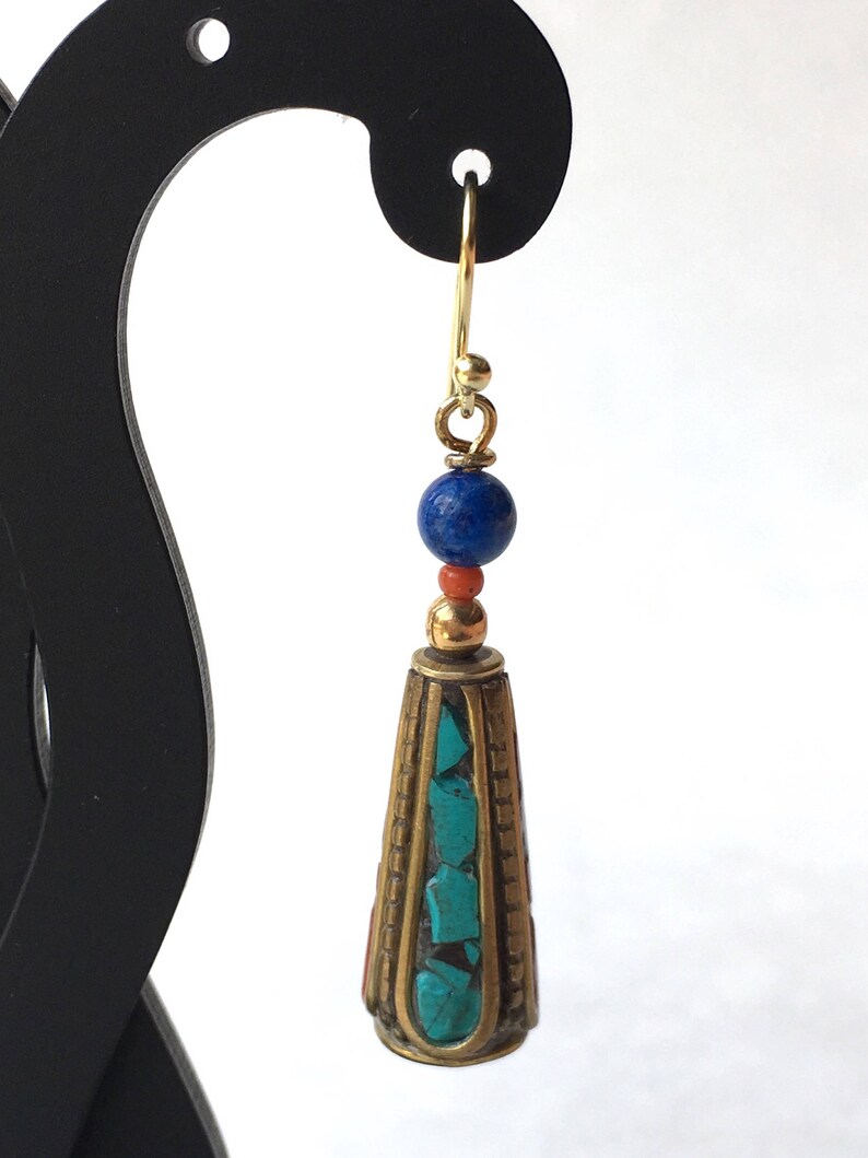 May include: Gold dangle earrings with a turquoise and coral stone cone pendant and a blue lapis lazuli bead.