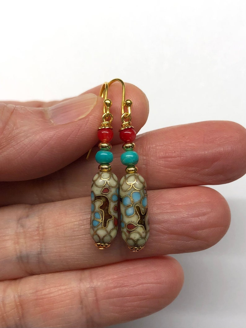 May include: A pair of gold dangle earrings with a white, blue, and red patterned bead, a turquoise bead, and a red bead on each earring.