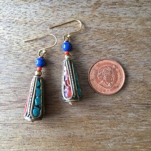 May include: A pair of dangle earrings with turquoise, coral, and lapis lazuli beads. The earrings are gold-toned and have a teardrop shape.