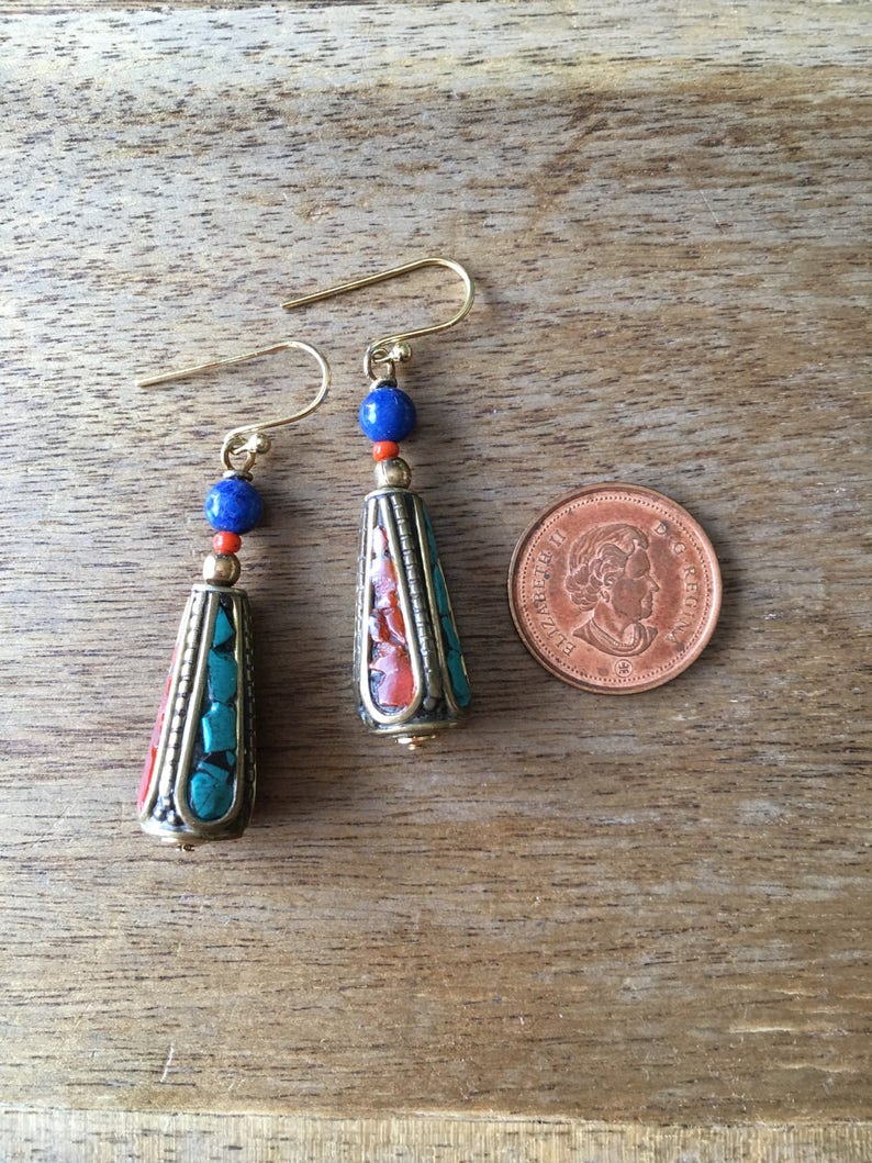 May include: A pair of dangle earrings with turquoise, coral, and lapis lazuli beads. The earrings are gold-toned and have a teardrop shape.