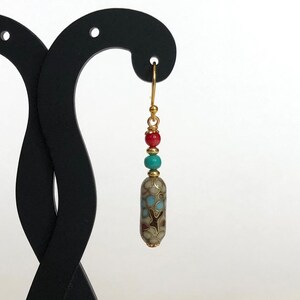 May include: Gold dangle earrings with a turquoise, red, and gold bead cluster and a patterned cylinder bead.