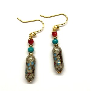 May include: Gold dangle earrings with a white, blue, and red patterned bead and three smaller beads in red and turquoise.