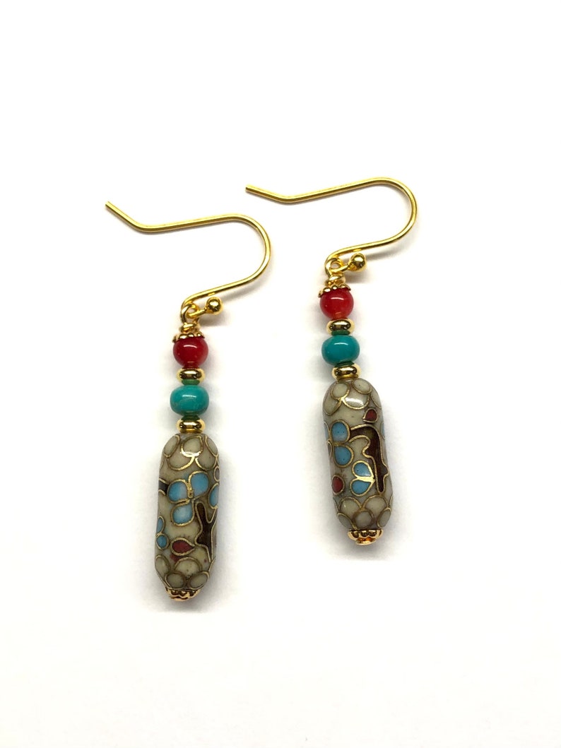 May include: Gold dangle earrings with a white, blue, and red patterned bead and three smaller beads in red and turquoise.