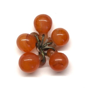 May include: A cluster of six orange glass beads connected by a metal ring. The beads are round and have a smooth, glossy finish.