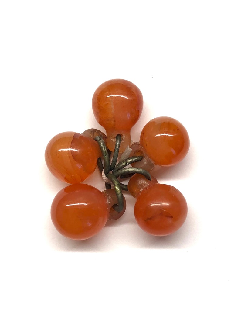 May include: A cluster of six orange glass beads connected by a metal ring. The beads are round and have a smooth, glossy finish.