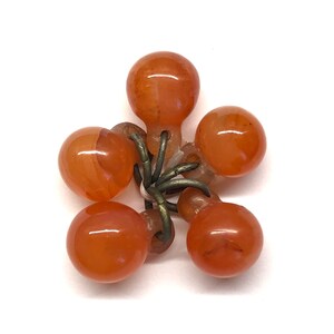 May include: A cluster of six orange carnelian beads connected by a metal wire. The beads are round and smooth.