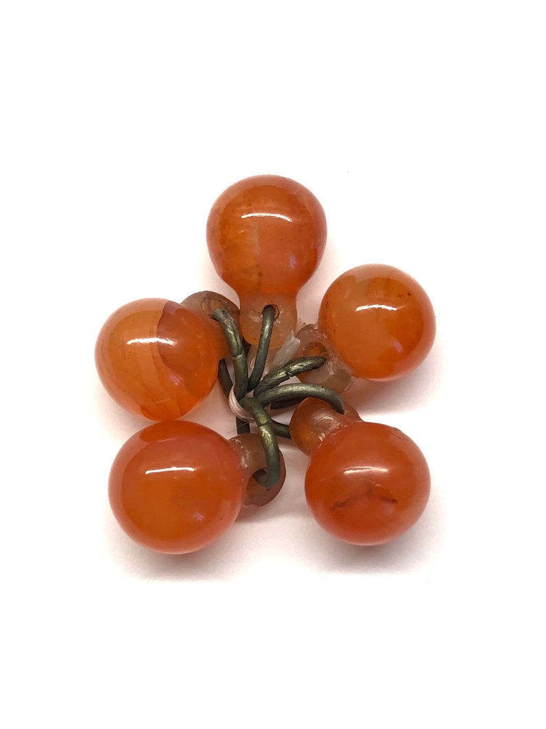 May include: A cluster of six orange carnelian beads connected by a metal wire. The beads are round and smooth.