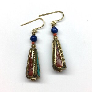 May include: A pair of gold dangle earrings with a blue and red stone bead and a gold cone-shaped pendant with red and blue inlay.