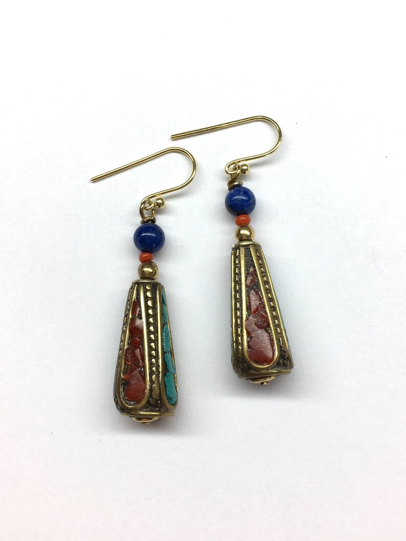 May include: A pair of gold dangle earrings with a blue and red stone bead and a gold cone-shaped pendant with red and blue inlay.