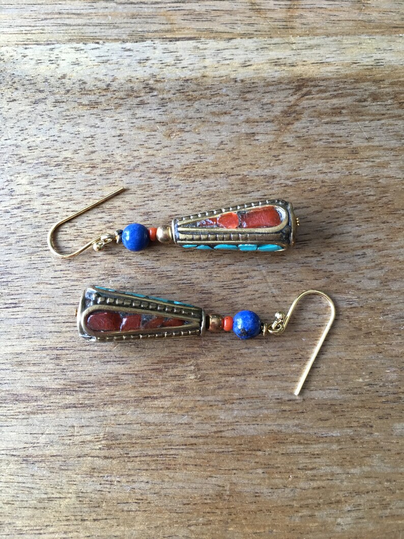 May include: A pair of dangle earrings with a gold tone metal setting. The earrings feature a blue and red stone with a turquoise accent.