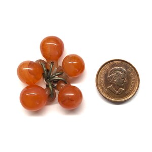 May include: A cluster of six orange glass beads with metal loops, attached to a metal chain. The beads are about the size of a Canadian penny.