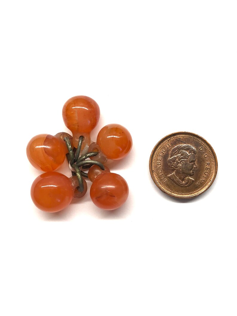 May include: A cluster of six orange glass beads with metal loops, attached to a metal chain. The beads are about the size of a Canadian penny.