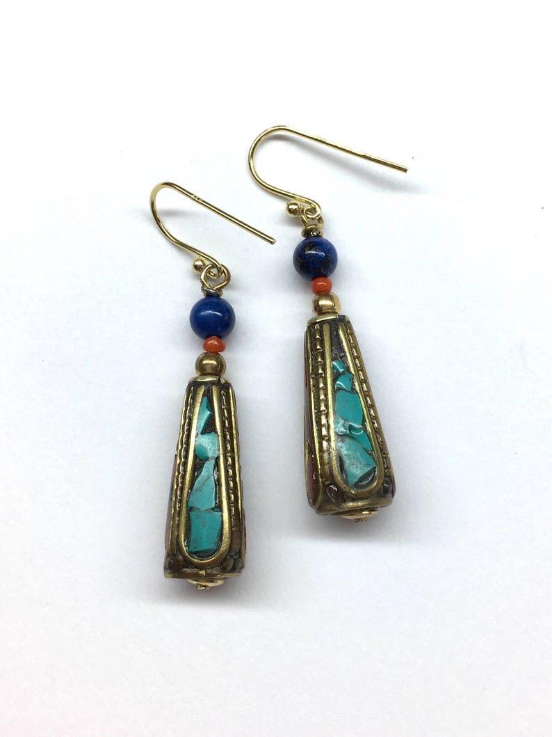 May include: A pair of gold dangle earrings with turquoise and red beads. The earrings have a teardrop shape and are accented with gold.