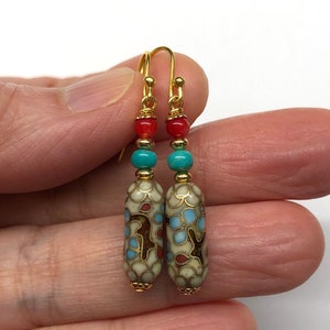 May include: Gold dangle earrings with a white, blue, and red patterned ceramic bead, a turquoise bead, and a red bead.