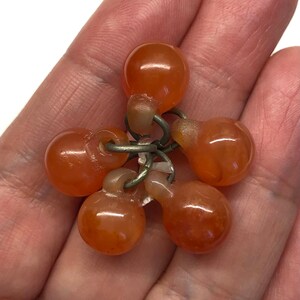 May include: A cluster of six orange carnelian beads connected by silver rings. The beads are smooth and polished.