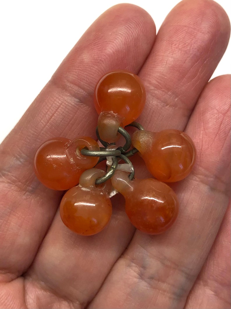 May include: A cluster of six orange carnelian beads connected by silver rings. The beads are smooth and polished.