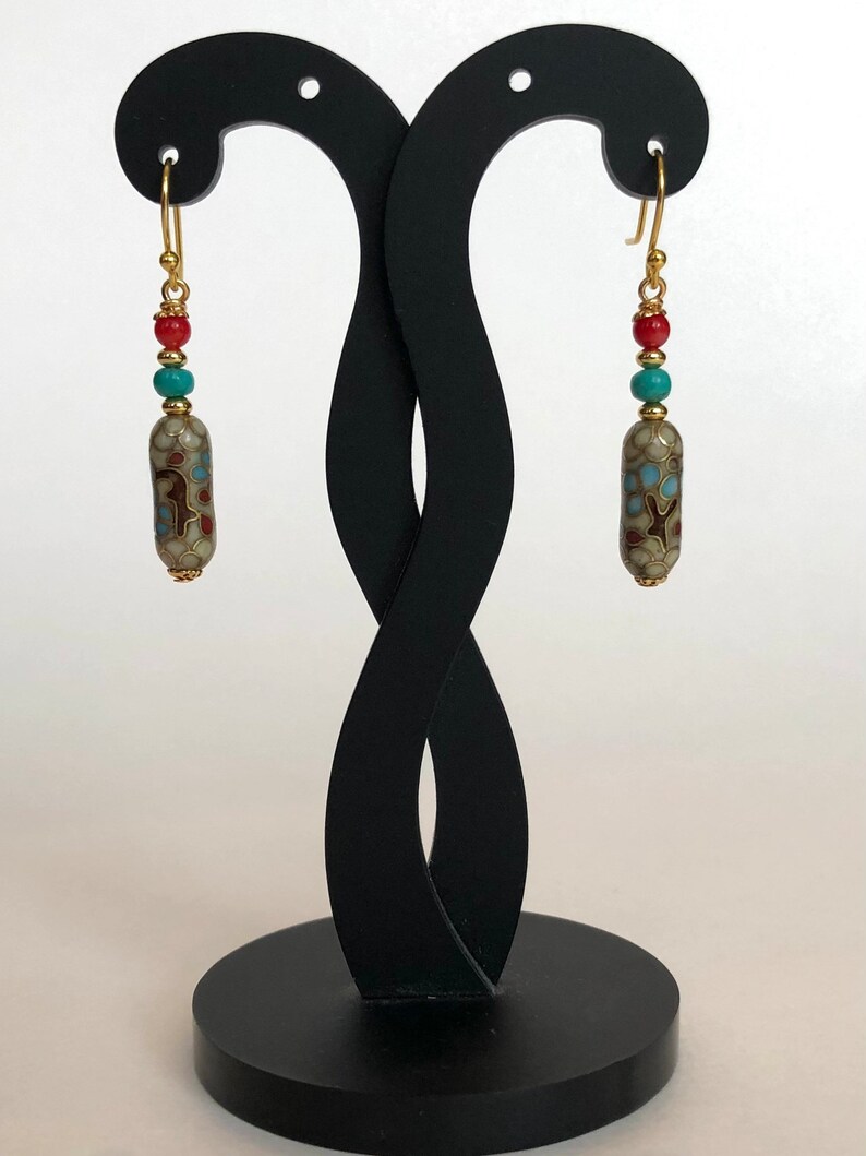 May include: A pair of gold dangle earrings with a white, brown, and blue patterned ceramic bead, a turquoise bead, and a red bead on each earring.