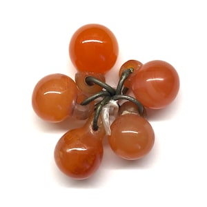 May include: A cluster of six orange carnelian beads connected by metal rings. The beads are smooth and polished, with a slight variation in shape and size.