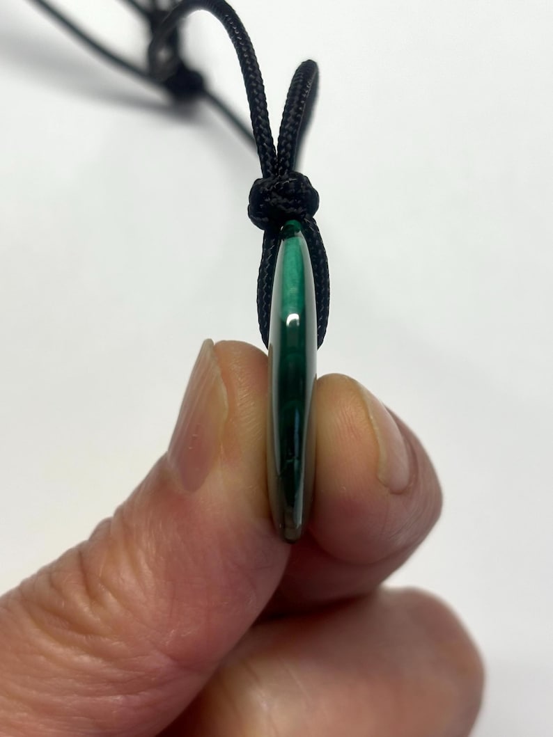May include: A green malachite stone pendant on a black cord necklace.