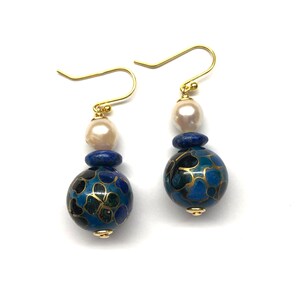 May include: Gold earrings with a blue and black cloisonn&eacute; bead, a lapis lazuli bead, and a white pearl.