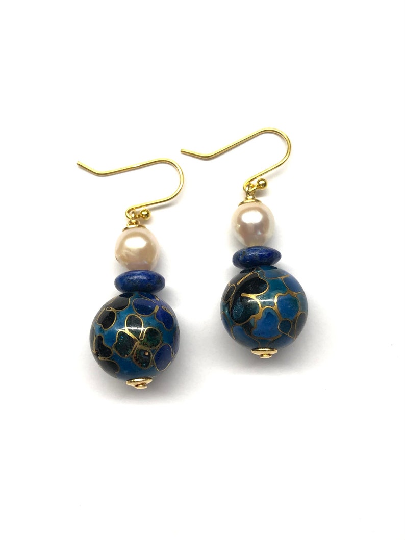 May include: Gold earrings with a blue and black cloisonn&eacute; bead, a lapis lazuli bead, and a white pearl.