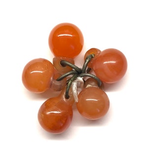 May include: A cluster of six orange carnelian beads connected by silver wire. The beads are teardrop shaped and have a smooth, polished finish.
