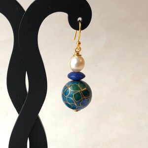 May include: Gold dangle earrings with a blue and green patterned sphere, a smaller blue sphere, and a white pearl.