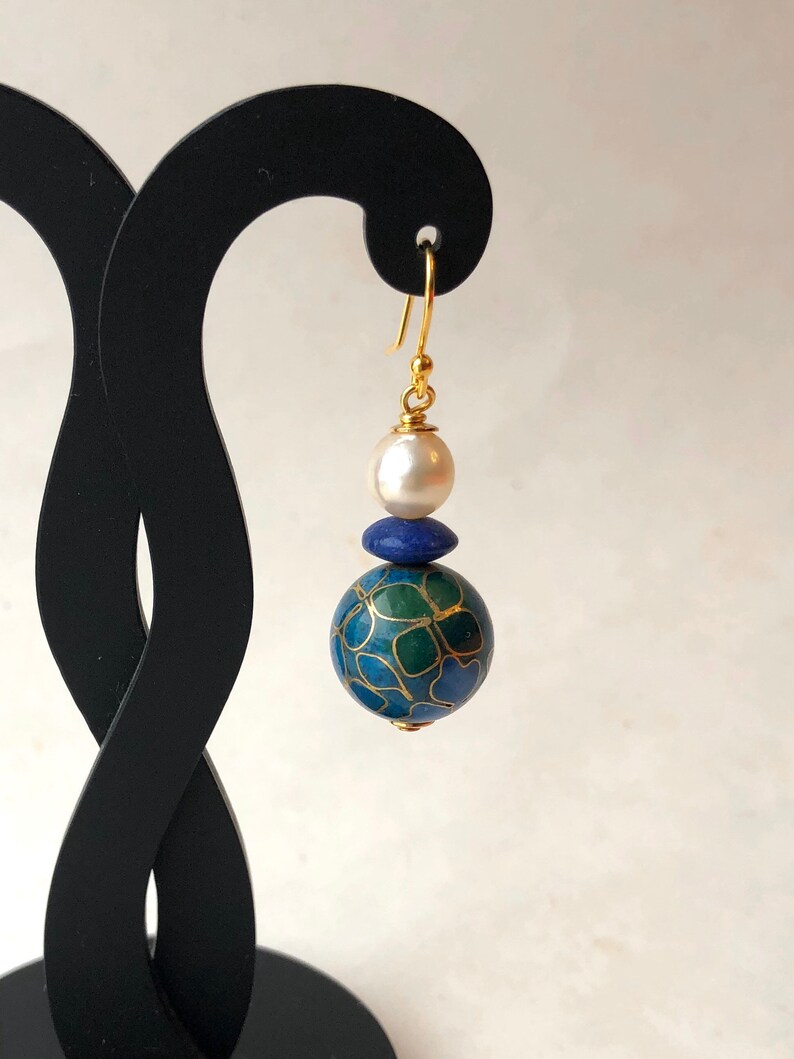 May include: Gold dangle earrings with a blue and green patterned sphere, a smaller blue sphere, and a white pearl.