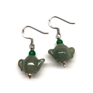 May include: Sterling silver earrings with green jade teapot charms and green jade beads. The earrings are marked "925" on the back.