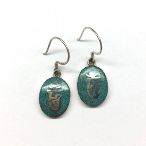 May include: A pair of silver earrings with turquoise blue oval-shaped charms. Each charm has a silver Chinese character etched into the surface.