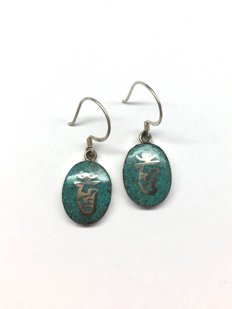 May include: A pair of silver earrings with turquoise blue oval-shaped charms. Each charm has a silver Chinese character etched into the surface.