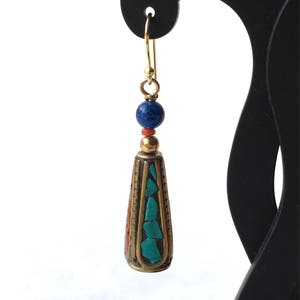 May include: Gold dangle earrings with a turquoise and red stone teardrop pendant and a blue bead.