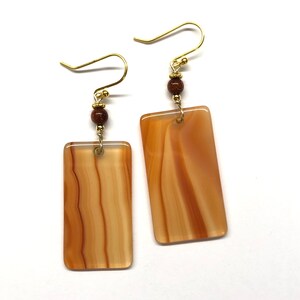 Peut inclure: Une paire de boucles d'oreilles en or avec des pendentifs rectangulaires en agate brune et des perles brunes.